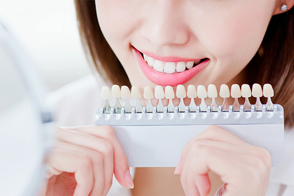 歯の白さが異なる歯の模型でホワイトニングによる希望の白さを確認している女性のイメージ