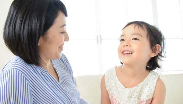 親と子どもが笑顔で見つめあっている家族写真