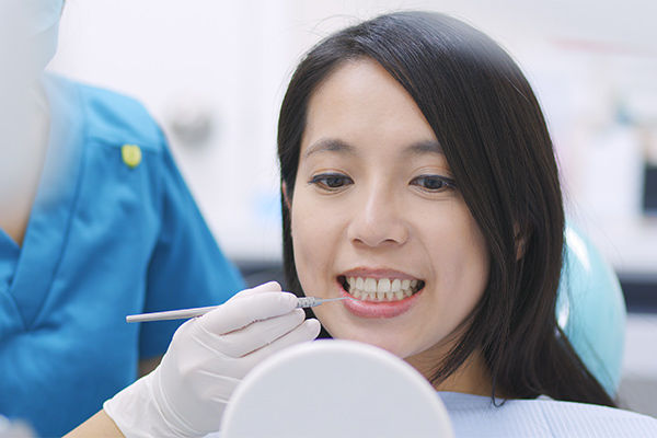 麻布十番の歯医者さんで歯科医師と歯の状態を手鏡で確認している女性のイメージ