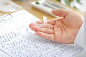 歯科医師がマウスピースの説明をしている写真