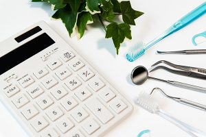 電卓と歯ブラシ、歯科治療で使用する器具の写真