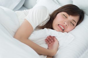 睡眠中に歯ぎしりや食いしばりをしている女性のイメージ