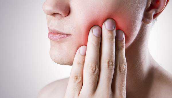 口内に違和感を感じ、手を頬に添えている写真